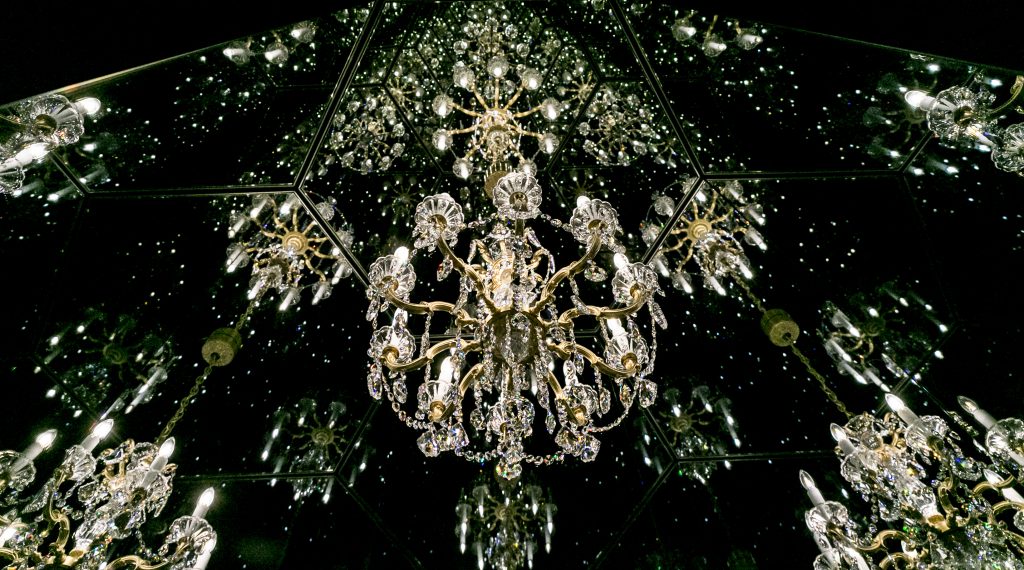 Der funkelnde Swarovski Kristall-Luster im Zentrum von Yayoi Kusamas Wunderkammer ãChandelier of GriefÒ spiegelt sich wieder und wieder in einem scheinbar endlosen Raum.