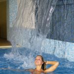 frau_unter_wasserfall_im_familienschwimmbad_wohlfuehlhotel_schiestl.jpg