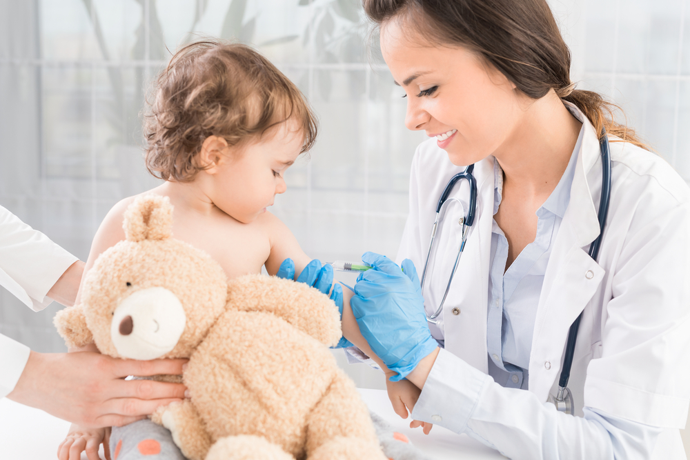 Kind mit Teddybär beim Impfen