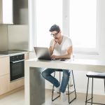 Handsome man using a laptop pc in the kitchen