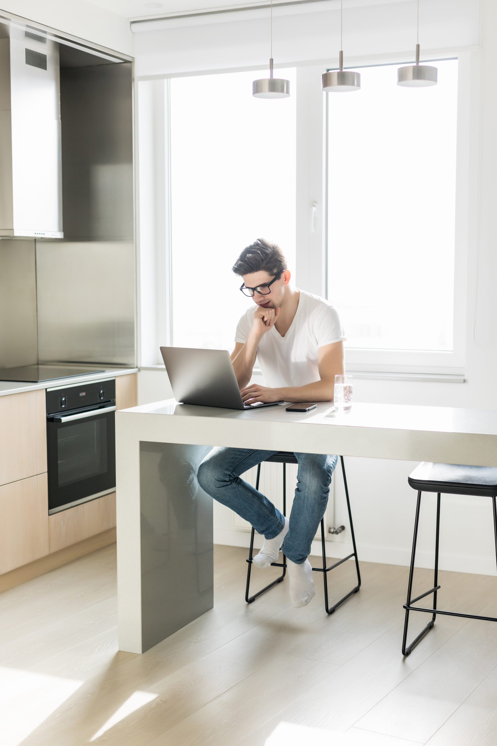 Handsome man using a laptop pc in the kitchen