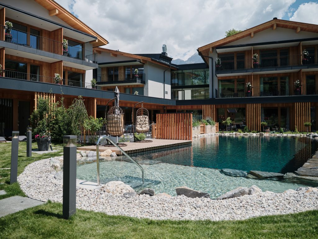 klarer_naturbadeteich_mit_blick_auf_das_hotel_c_youngmedia_hotel_morgenzeit