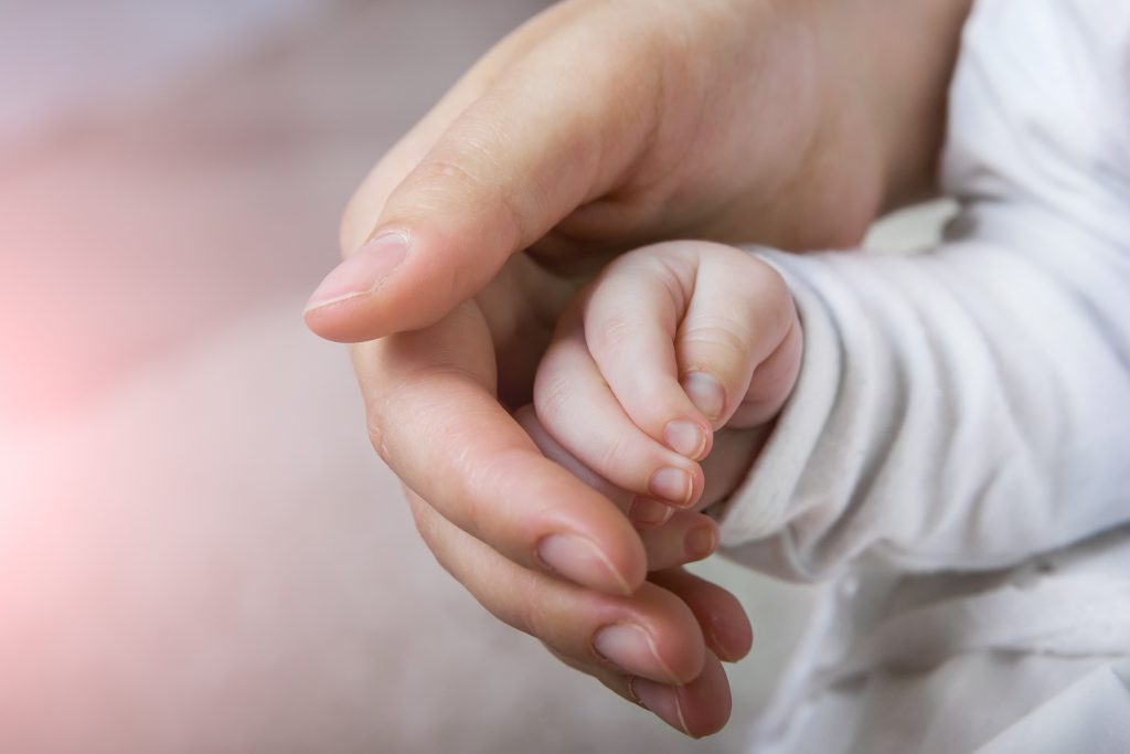 Female hand holding newborn baby's hand