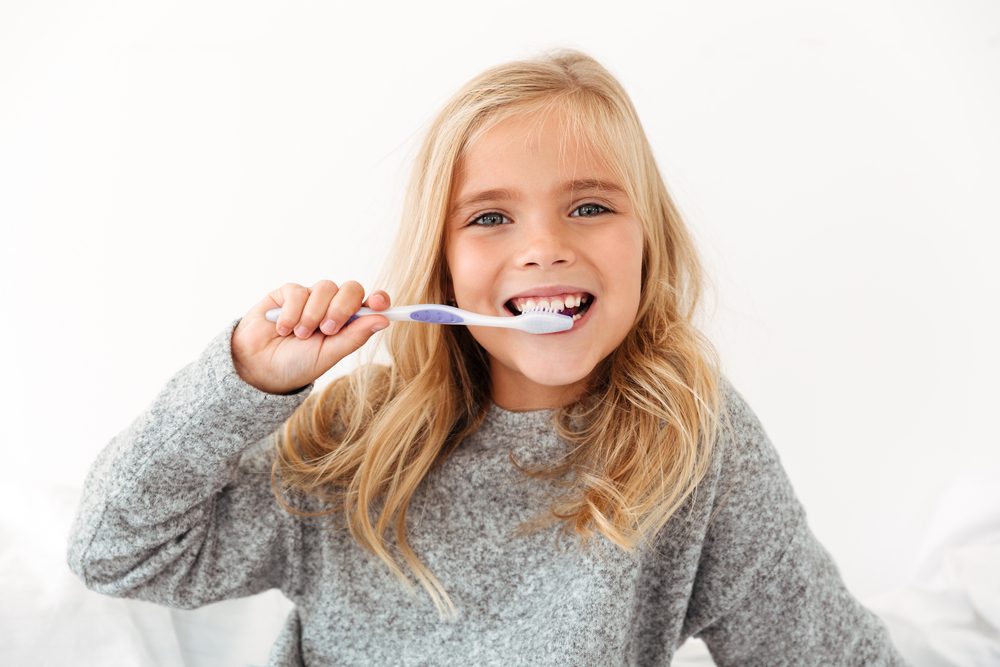 Close-up,Portrait,Of,Female,Kid,Brushing,Her,Teeth,,Looking,At