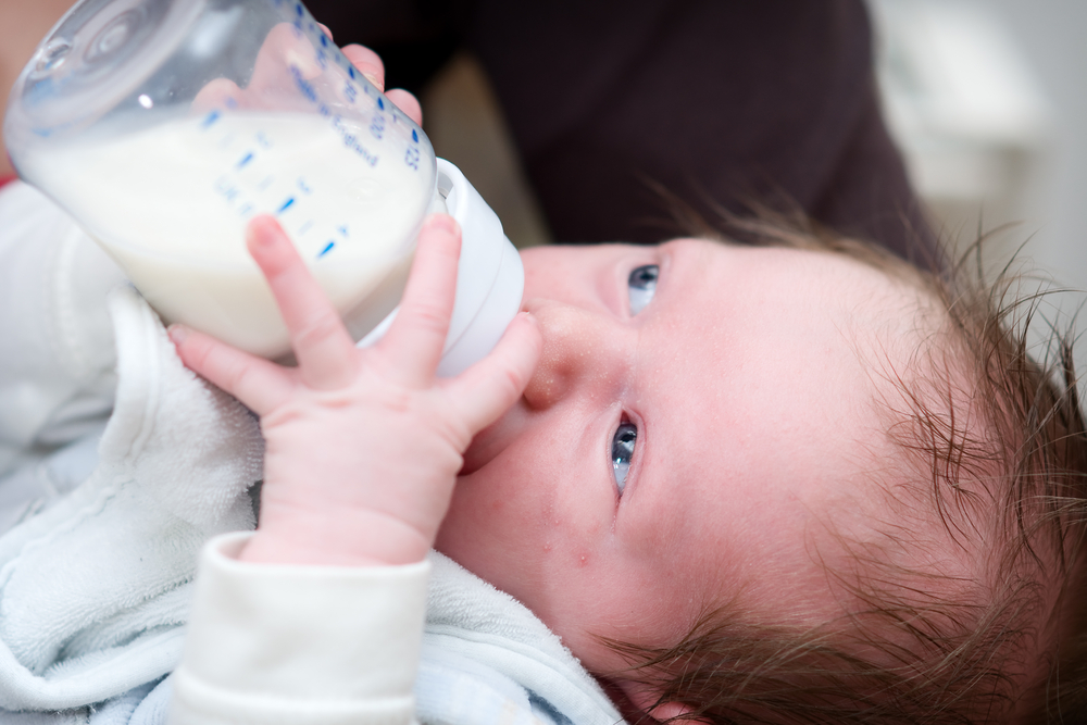 Little,Baby,Drinking,Milk,From,A,Bottle,With,Baby,Bib