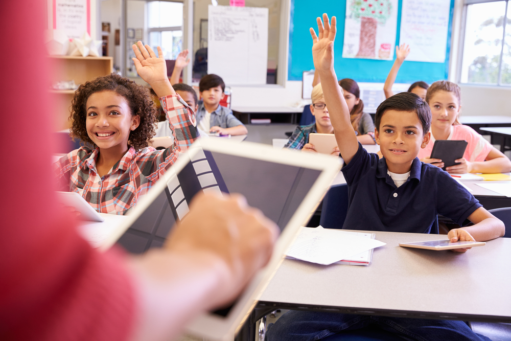 Teacher,Using,Tablet,Computer,In,Elementary,School,Lesson