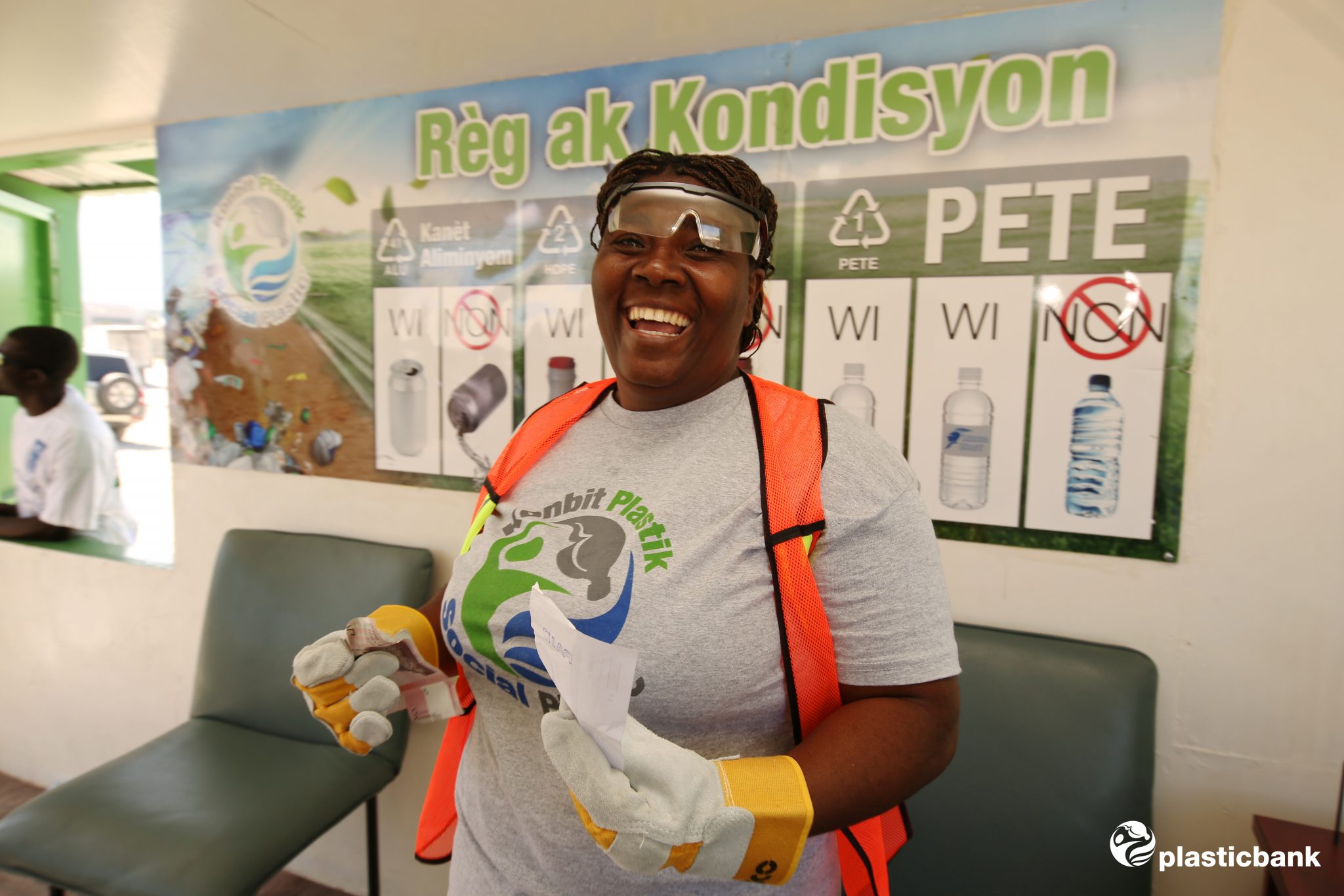 A female in a Social Plastic t-shirt and safety equipment inside a branch. Big smile/laugh.