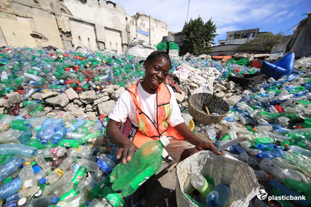 a female collector processes bottles in a yard in Haiti