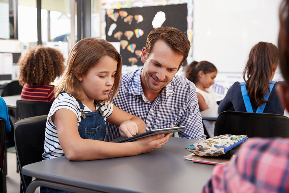 Teacher,And,Young,Schoolgirl,Using,Tablet,In,Classroom