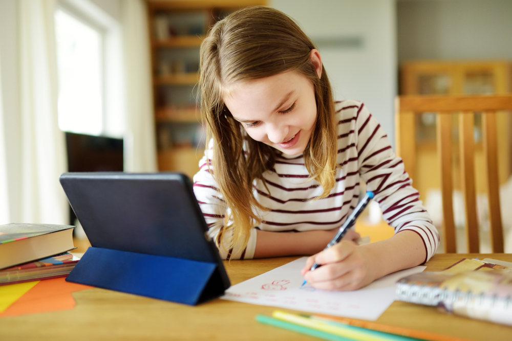 Preteen,Schoolgirl,Doing,Her,Homework,With,Digital,Tablet,At,Home.