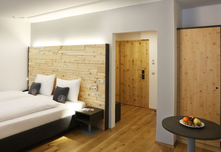 Sie sehen ein Doppelbett in einem Doppelzimmer im JUFA Alpenhotel Saalbach**** mit Obstschale. JUFA Hotels bietet erholsamen Familienurlaub und einen unvergesslichen Winterurlaub.