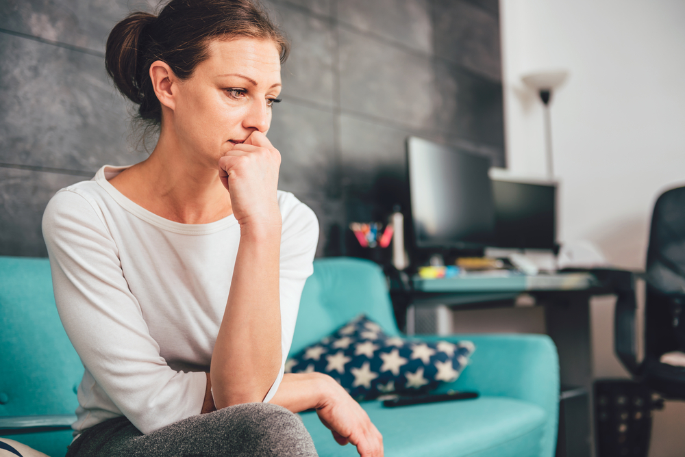 Sad,Woman,Sitting,On,A,Sofa,In,The,Living,Room