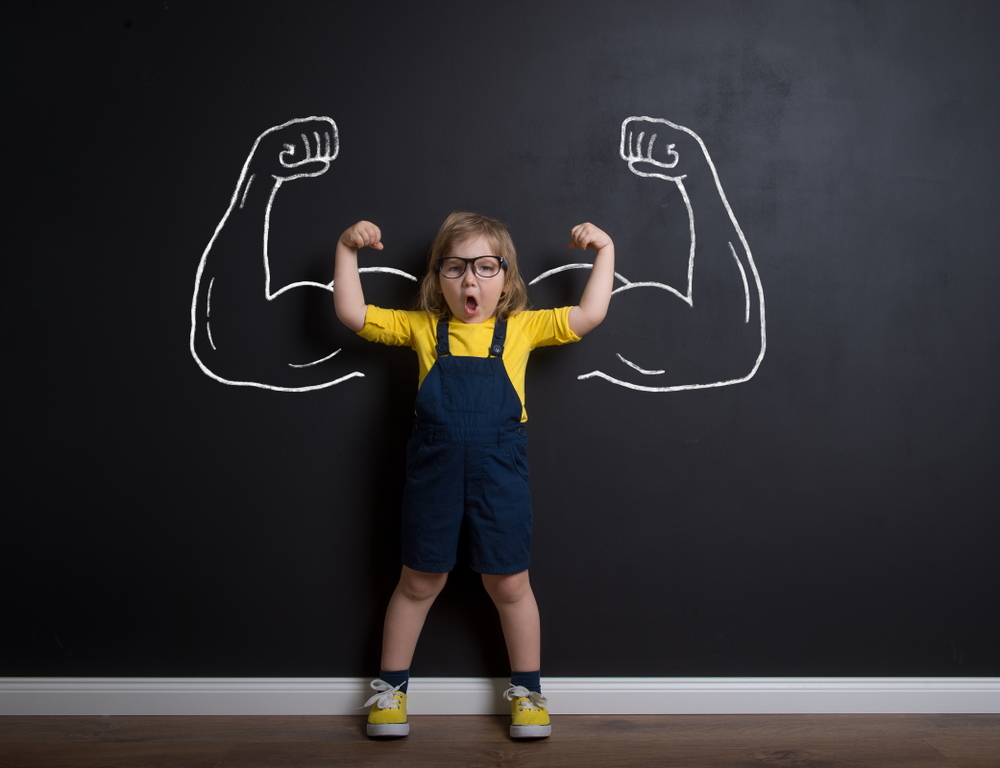 Child,Standing,Near,Chalkboard,With,Muscles,On,It.,Happy,Superhero