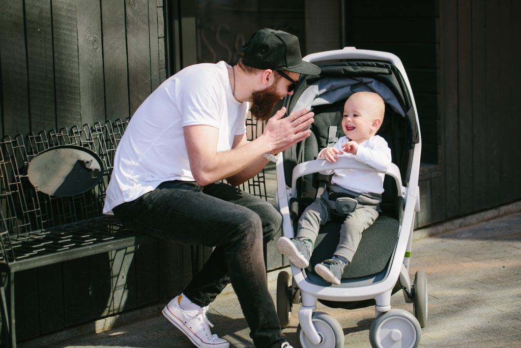 Father walking with a stroller and a baby in the city streets