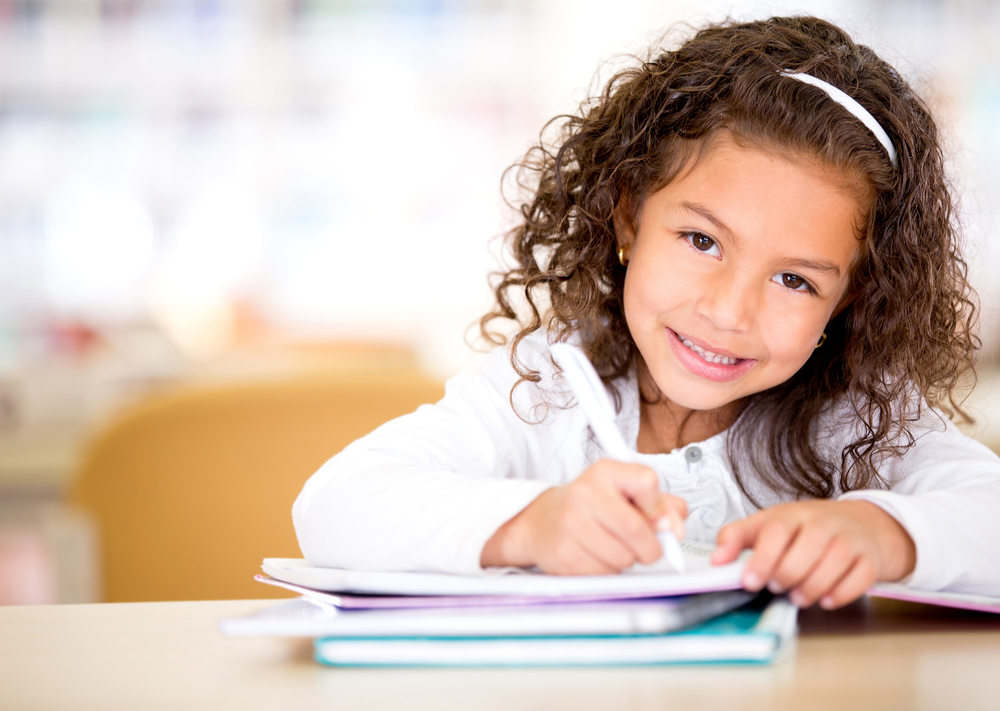 Cute,Little,Girl,Studying,At,The,Library,And,Smiling