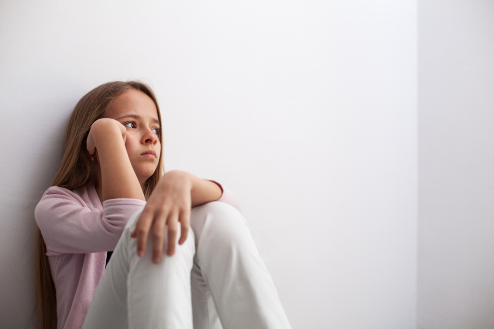 Pensive,Young,Teenager,Girl,Sitting,By,The,Wall,On,The