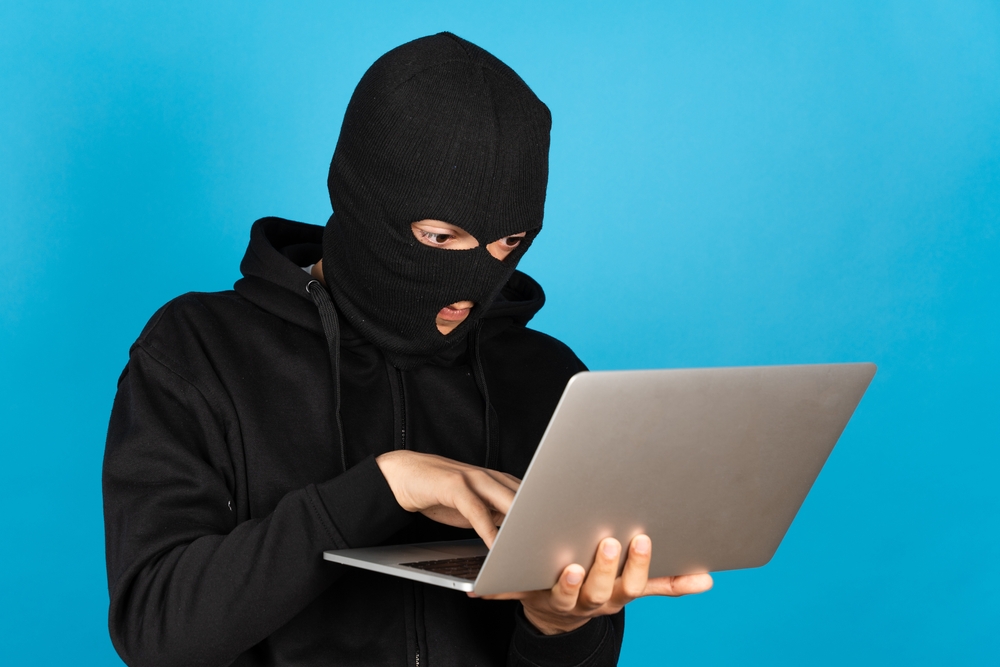Hacker,Or,Online,Criminal,Typing,On,Laptop,Isolated,On,Blue