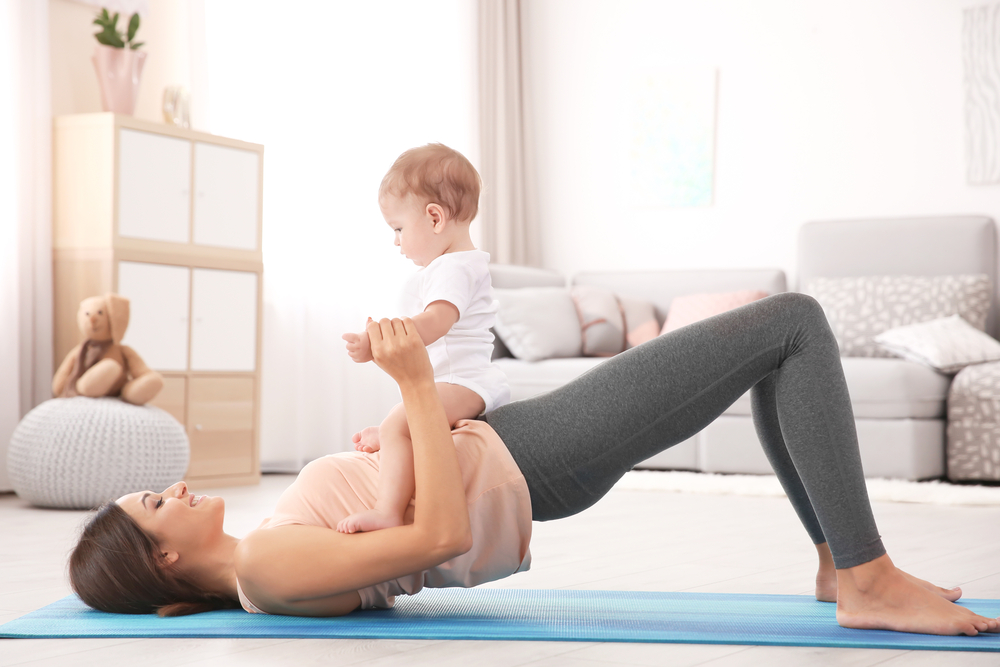 Young,Mother,Doing,Yoga,With,Baby,At,Home