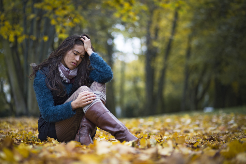 Depressed,Young,Woman,Sitting,In,A,Park,Full,Of,Autumn