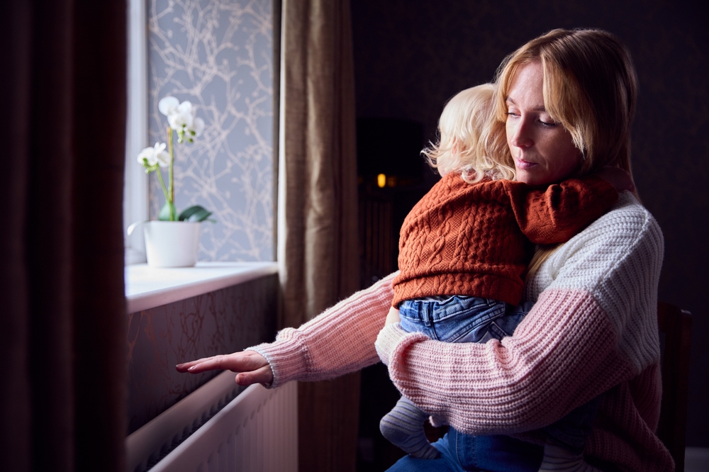 Mother,With,Son,Trying,To,Keep,Warm,By,Radiator,At