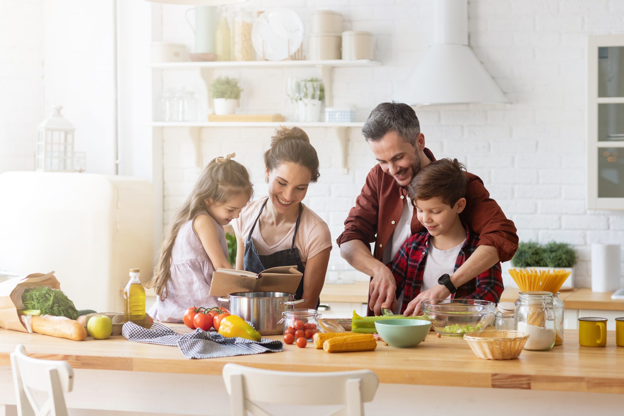 Glckliche Familie beim gemeinsamen Kochen in der Kche. Mutter und Tochter lesen Vater und Sohn das Rezept vor. Vater und Junge hacken grnes Gemseblatt fr Salat. Erholung und Lebensmittelzubereitung am Wochenende. Das Bild darf nur in Verbindung mit der Pressemitteilung verwendet werden. / Die Verwendung dieses Bildes fr redaktionelle Zwecke ist unter Beachtung aller mitgeteilten Nutzungsbedingungen zulssig und dann auch honorarfrei. Verffentlichung ausschlie§lich mit Bildrechte-Hinweis.