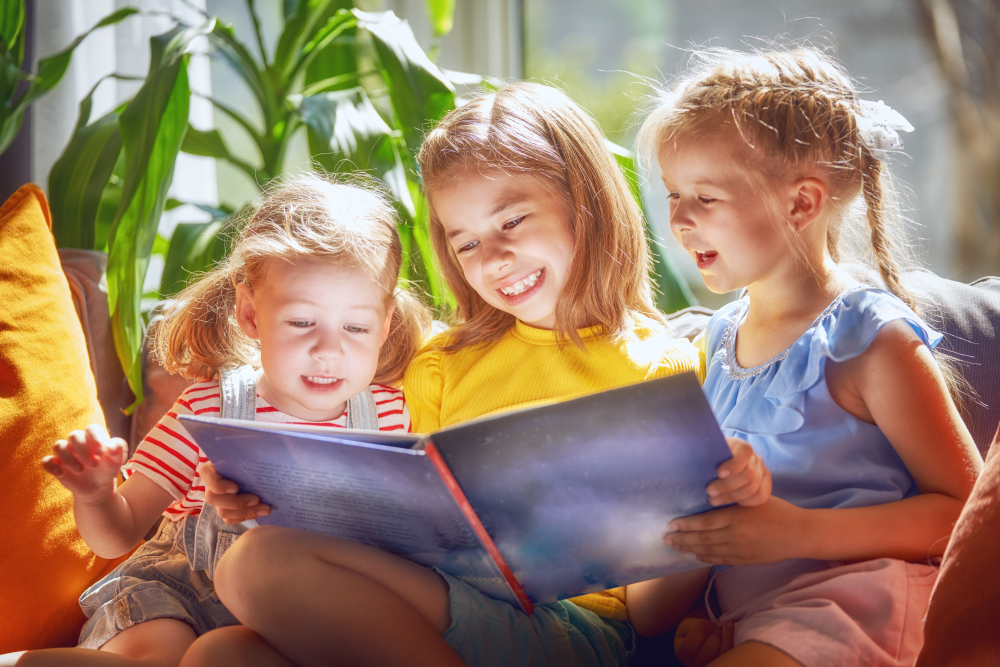 Cute,Children,Girls,Are,Reading,A,Book,Sitting,On,Sofa