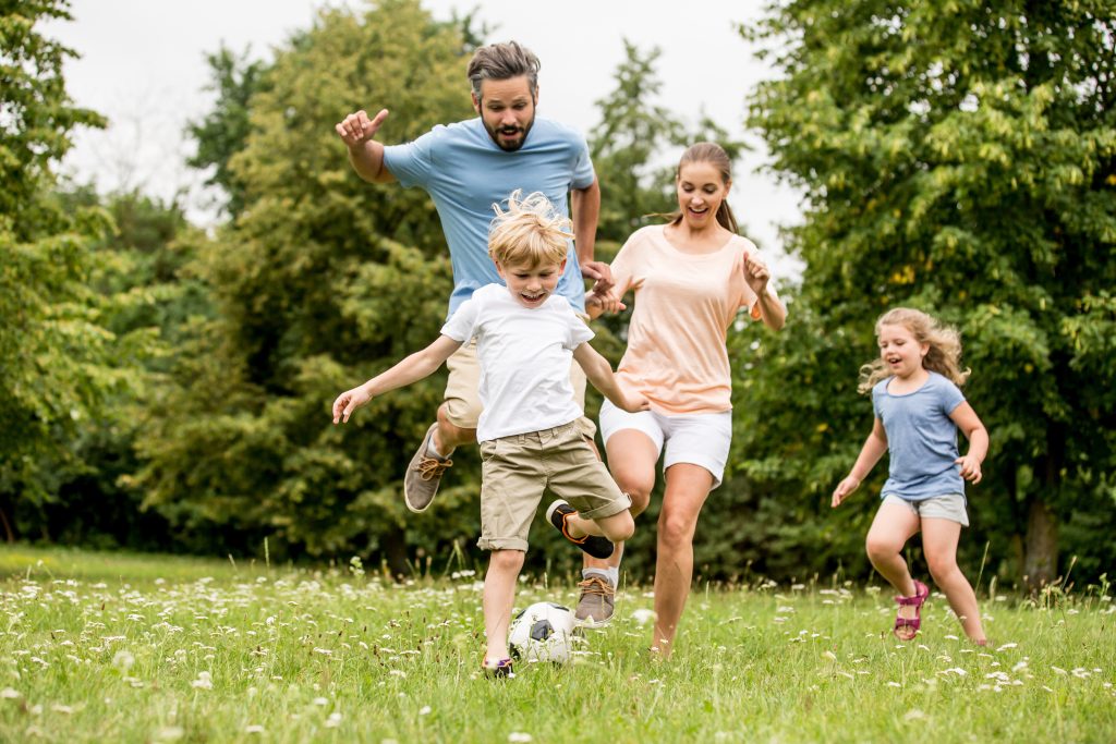 Familie spielt zusammen Fußball in der Freizeit auf einer Wiese