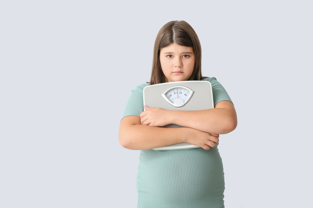 Sad,Overweight,Girl,With,Measuring,Scales,On,Light,Background