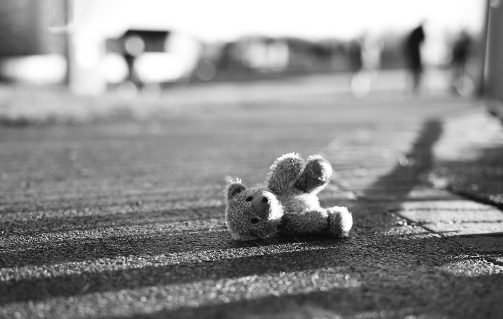 Teddy,Bear,With,Sad,Face,Lying,On,Footpath,With,Blurry