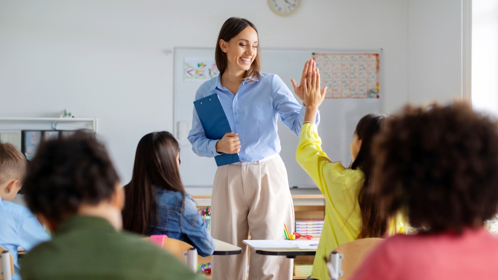 Cheerful,European,Female,Teacher,Giving,High,Five,To,Pupil,Girl